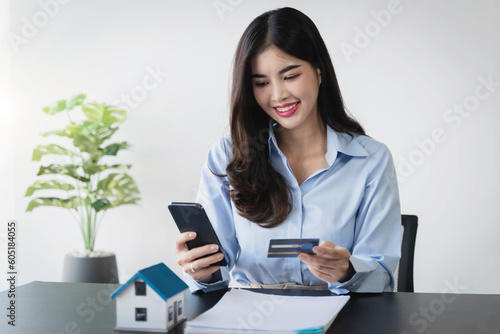 Woman using credit card and mobile phone for online shopping purchasing, buying at home, paying bills from home.