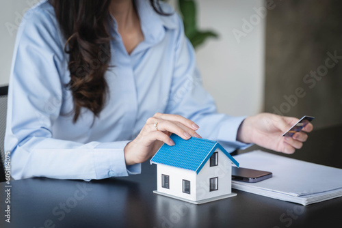 House model and woman holding credit card on the table.Property purchase idea, Interest rate for housing, Business and Financial for residence, Money saving for home concept.