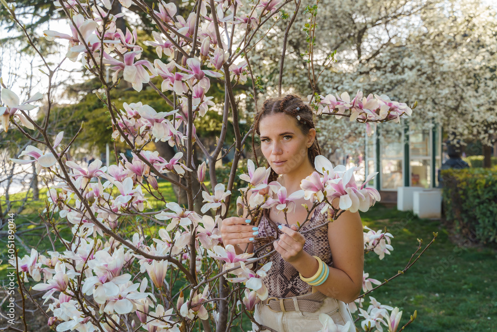 Magnolia flowers. Happy woman enjoys by blooming magnolia tree and sniffs it flowers with closed eyes in spring garden. Portrait. Magnolia flowers. Happy woman enjoys by blooming magnolia tree and sniffs it flowers with closed eyes in spring garden. Portrait.