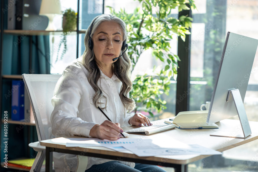 Good-looking mature business woman at the computrer looking busy Good-looking mature business woman at the computrer looking busy