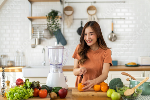 Portrait of beauty body slim healthy asian woman drinking glass of juice and orange.young girl preparing cooking healthy drink with fresh orange juice in kitchen at home.Diet concept.healthy drink © Art_Photo