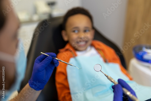 Dark-skinned cute boy looking frightened while sitting at the dentists office