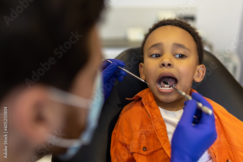 Scared little boy sitting with open mouth at the dentists chair