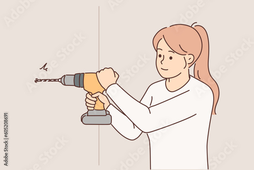 Woman uses electric drill to create hole in wall and hang shelf or picture in apartment