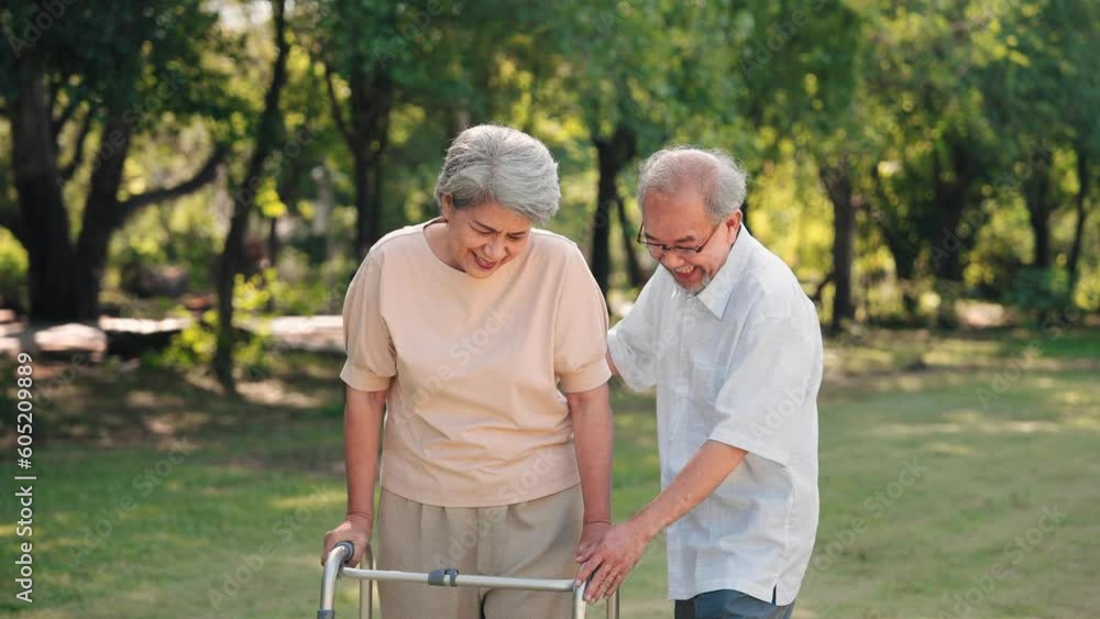 Asian senior husband take care to wife having knee pain while walking with walker stick in the park, Physical therapy in outdoor concept Asian senior husband take care to wife having knee pain while walking with walker stick in the park, Physical therapy in outdoor concept