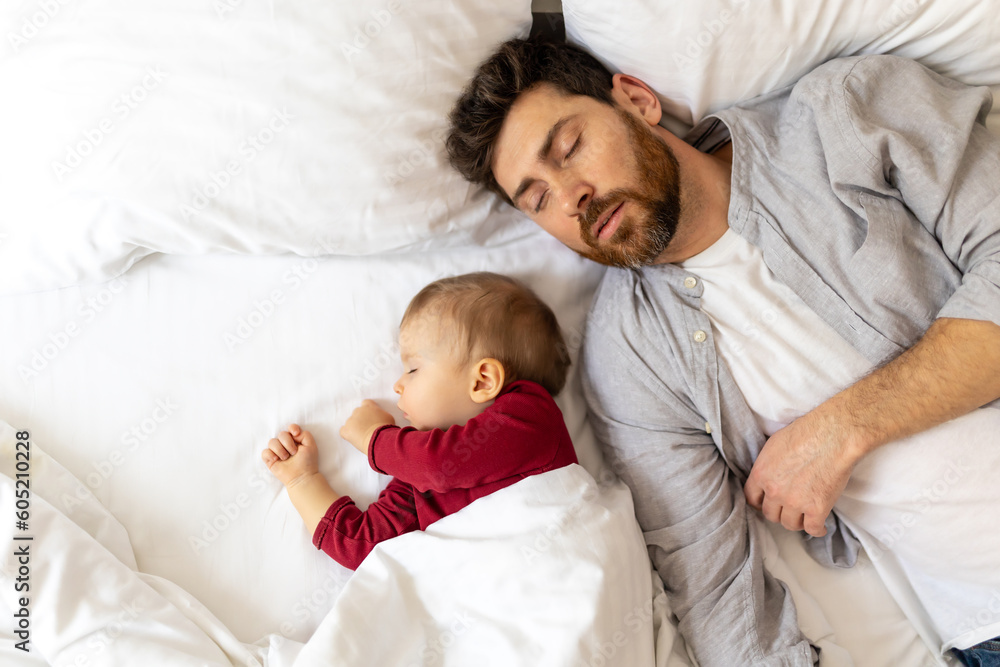 Bearded man sleeping together with infant daughter in bed.