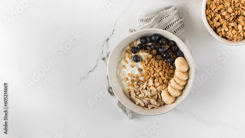 Homemade granola with Greek yogurt, almonds, blueberries and banana in a bowl. Copy space