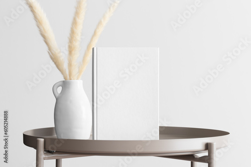 White book mockup with a pampas decoration on the beige table.