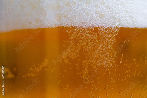 Pouring beer with bubble froth in glass background on front view