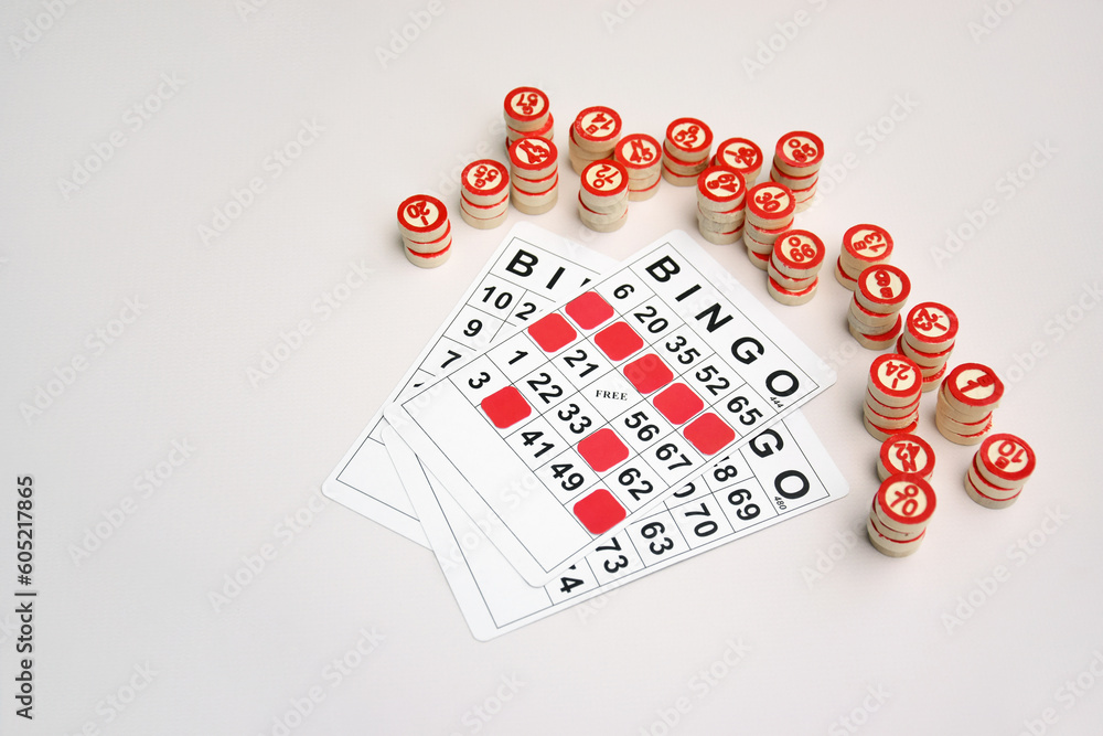 Many wooden chips with numbers and cards for a board game of bingo or lotto on a light background. Many wooden chips with numbers and cards for a board game of bingo or lotto on a light background.