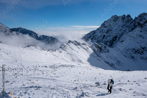 Hiker woman standing and looks around, admiring winter mountain landscape. Happy tourist woman in winter. High Tatras, 1987 meter above sea level. Slovakia © Martin