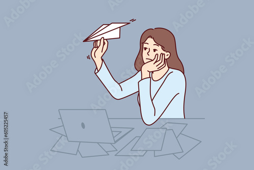 Unmotivated woman freelancer procrastinating sitting at office desk with laptop and launching paper planes. Unmotivated office worker needs support from manager or help with burnout.