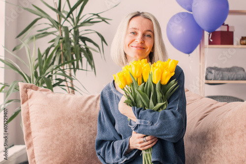 Happy adult woman hold bouquet of flowers at home