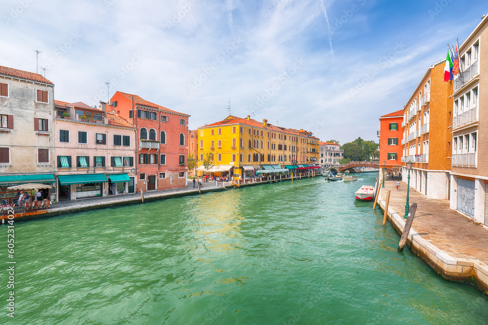 Gorgeous cityscape of Venice with narrow canals, boats and gondolas and bridges with traditional buildings
