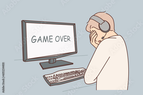 Gamer lost in videogame and got upset when saw inscription game over on computer monitor