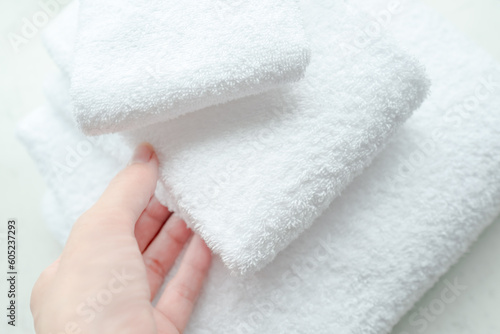上質な無地の白いタオルに触れている女性の手 - たたんで重ねた色々なサイズの真っ白で清潔なタオル
