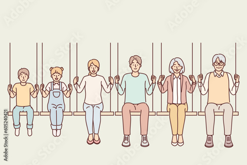 Different generations from family with parents and children with grandchildren sitting on swing