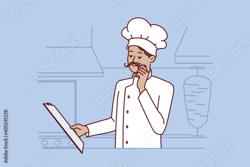 Chef cook man stands in kitchen street food restaurant and holds clipboard with menu getting ready for new working day. Chef guy makes career in restaurant industry and touches mustache