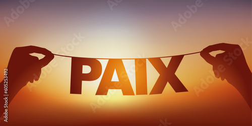 La silhouette du mot paix écrit en lettres détachées sur une guirlande face à un coucher de soleil.