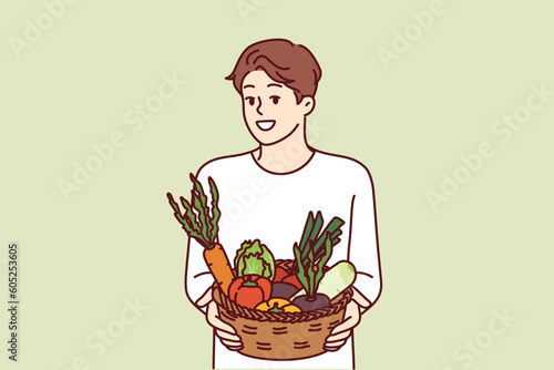 Man with basket of vegetables smiles and recommends going vegan or eating organic raw food. Vegetarian guy offers to buy farm vegetables and start new healthy diet to improve health