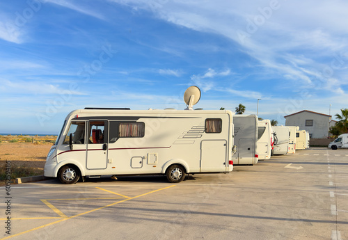 Campervan in camp parking near beach at coastline. Family rv camper van vehicle at seaside. Rving motorhome lifestyle travel to sea. Travel on Campervan along Spain coast. Caravaning Parking. Camping