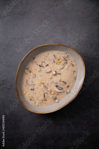 Top view of a bowl of creamy mushroom soup against a grey background with plenty room for a copy