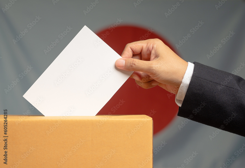 Election in Japan. Hand voter holding ballot paper putting into the