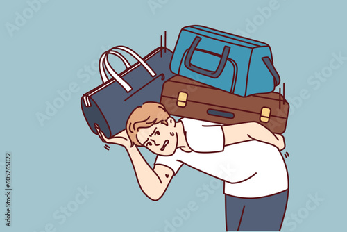 Dissatisfied man with heavy suitcases is moving or relocating to new city. Guy in casual clothes bends over putting suitcases on back and looks at screen in need of help from loader