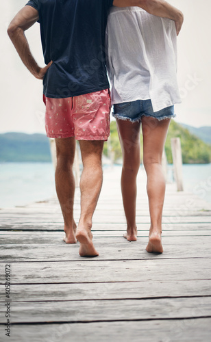 Couple, relax walking and beach deck on holiday with freedom and love in summer in Thailand. Tropical nature, sea and back of people on a boardwalk walk in the sun on vacation break by ocean water