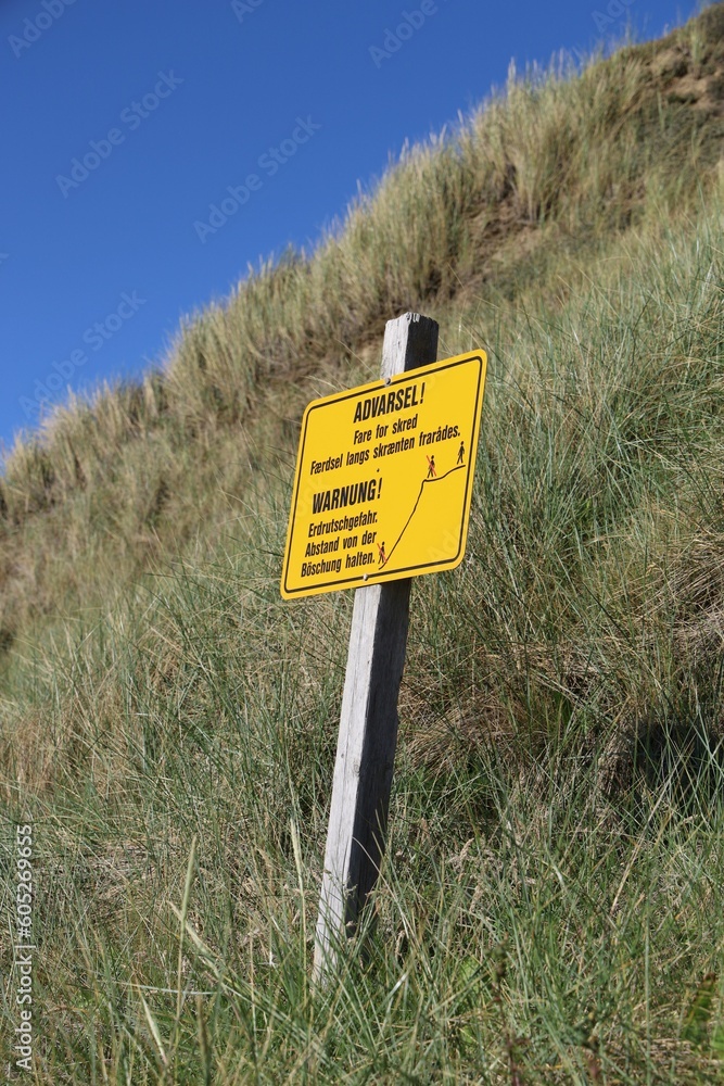 Vertical shot of a warning sign on a steep slope of a hill