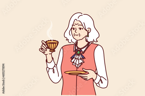 Elderly rich aristocrat woman drinks tea from golden mug and is dressed in exquisite expensive clothes with elegant accessories. Arrogant old woman is aristocrat and personifies power or snobbery.