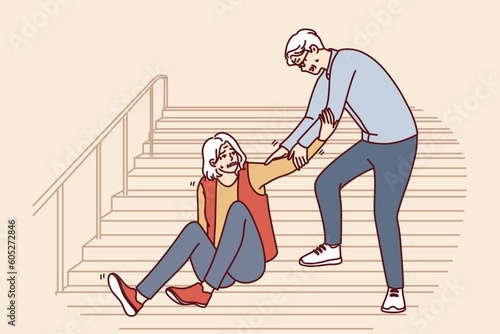 Elderly man helps fallen old woman up while descending street staircase. Gray-haired caring grandfather provides first aid to grandmother who has fallen on walk and descending stairs