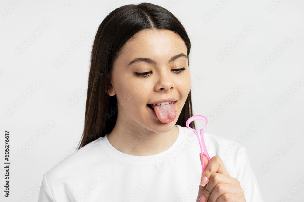 Young caucasian girl cleaning tongue isolated on white background. Health care, mouth hygiene Young caucasian girl cleaning tongue isolated on white background. Health care, mouth hygiene