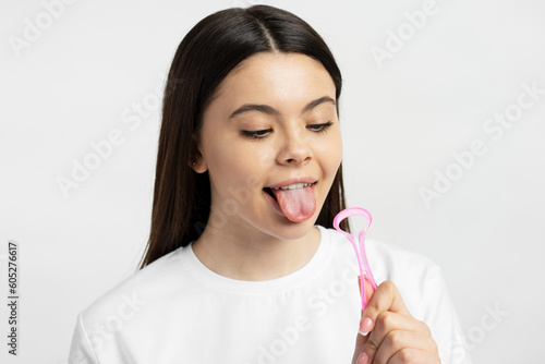 Young caucasian girl cleaning tongue isolated on white background. Health care, mouth hygiene 
