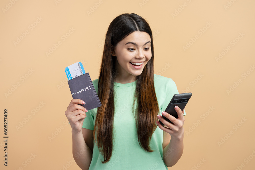 Portrait of cute smiling teenage girl holding mobile phone, passport with travel pass isolated on background Portrait of cute smiling teenage girl holding mobile phone, passport with travel pass isolated on background