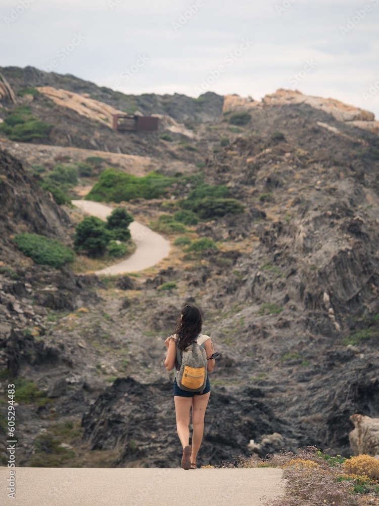 Aerial view of female walking through road in background of rocky mountains in Cap de Creus