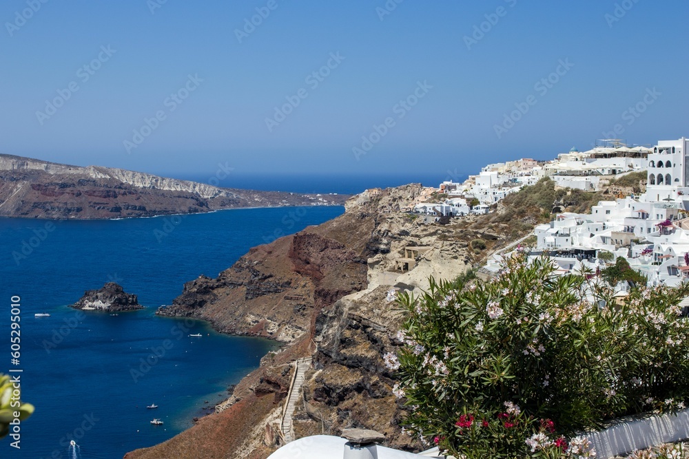 Aerial view of Oia village buildings on the coastal cliff on a sunny day in Greece