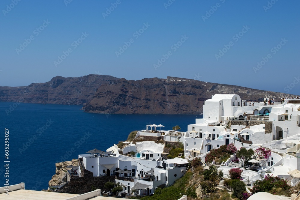 Aerial view of Oia village marble buildings before the sea on a sunny day in Greece