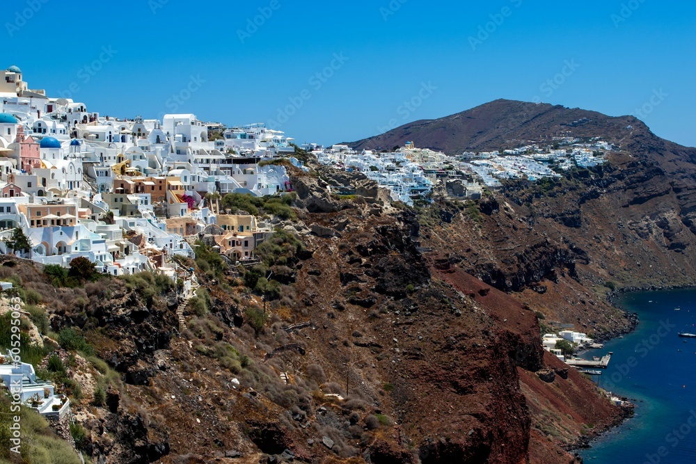 Aerial view of Oia village buildings on the coastal cliff on a sunny day in Greece