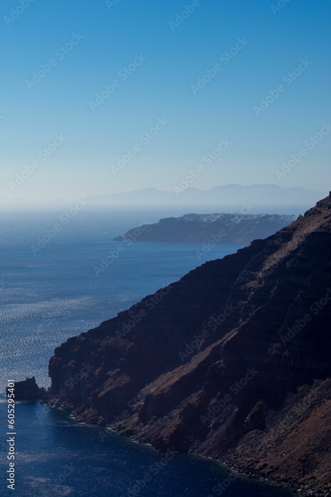 Vertical shot of a blue ocean in summer with a blue sky in the background in Oia, Santorini