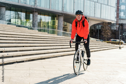 Courier delivery of documents and materials for the office. A male cyclist in a helmet riding a bicycle ecotransport to work with a bag. photo