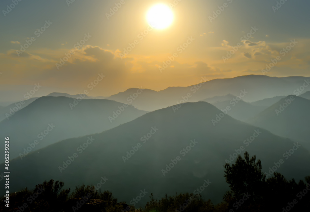 Naklejka premium Mountains landscape on sunset. Mountain view from Mola De Segart mountain in Sierra Calderona national park in Valencia, Spain. Sunset over mountains. Landscape of a mountain valley. Hill on sunrise.
