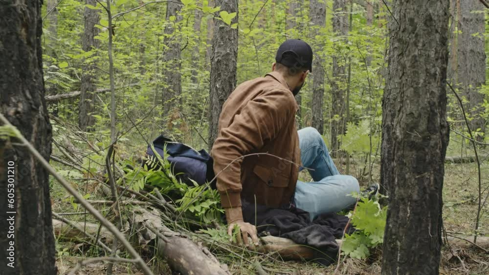 Full shot of young male Biracial tourist laying down to sleep on self-made bed in forest Full shot of young male Biracial tourist laying down to sleep on self-made bed in forest