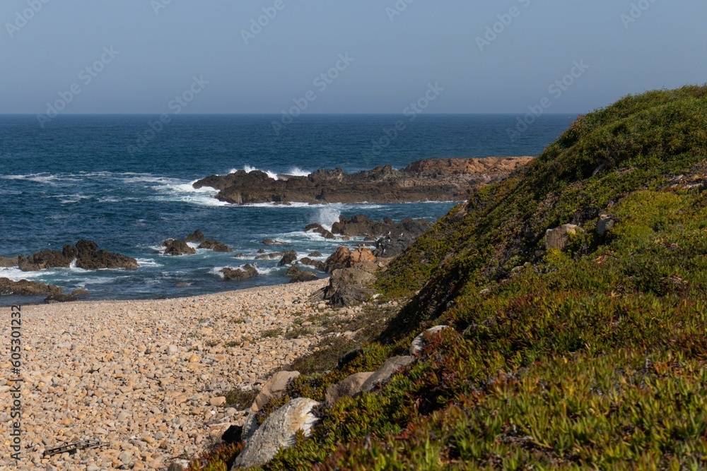 Shore of the sea covered with rocky mountains and waves of water in the background