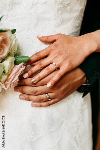 Φωτογραφία Vertical shot of the bride and the bridegroom holding hands with rings during th