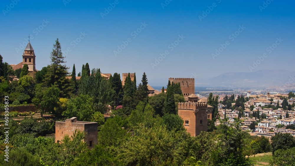 View of Saint Mary of the Alhambra and palace towers surrounded by green trees. Granada, Spain.