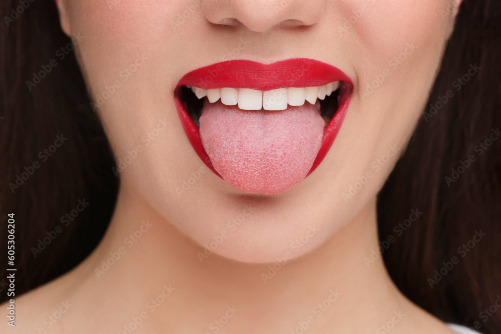 Fototapeta premium Woman with red lipstick showing her tongue, closeup