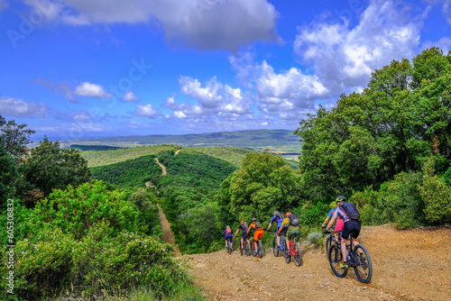 Fényképezés Unrecognisable mountain bikers ride on a firebreak trail over the beautiful land