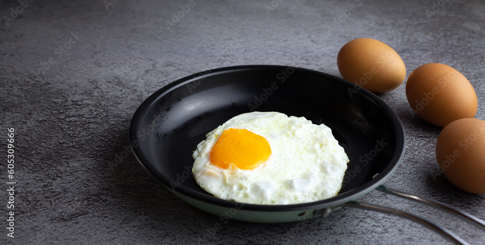 Top view of Breakfast menu fried eggs in an iron pan and raw chicken eggs. Top view of Breakfast menu fried eggs in an iron pan and raw chicken eggs.