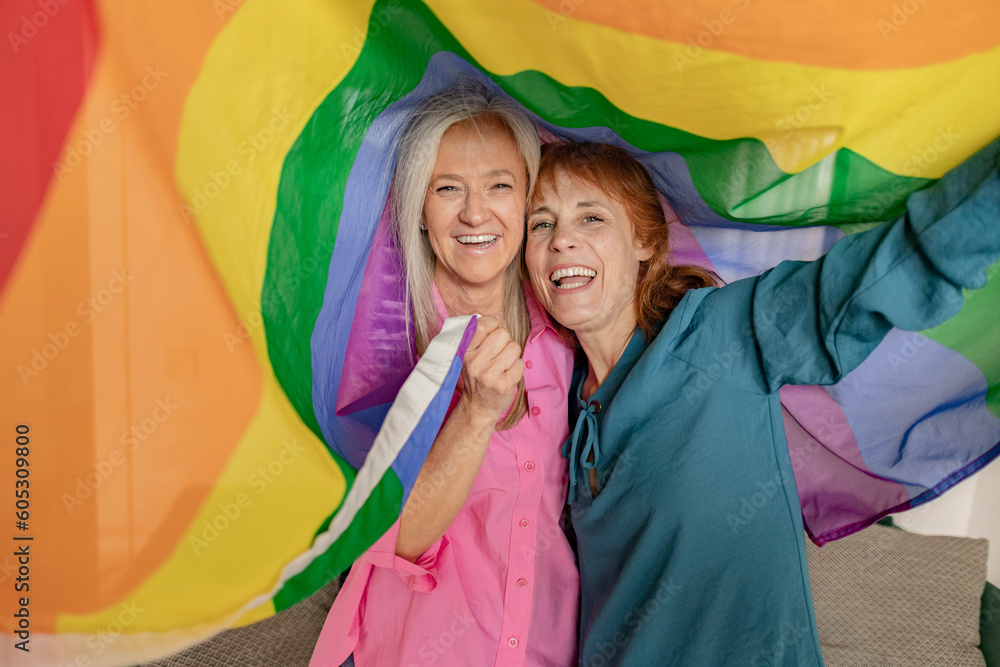 two senior mature women hoist the gay rainbow flag. I support the lgbti, gay, homosexual, bisexual, lesbian, trans, non-binary community. Fight for freedom and rights - obrazy, fototapety, plakaty 